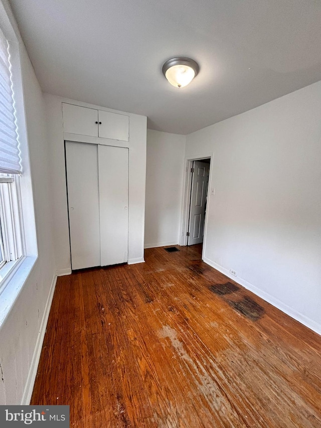 unfurnished bedroom with a closet and dark wood-type flooring