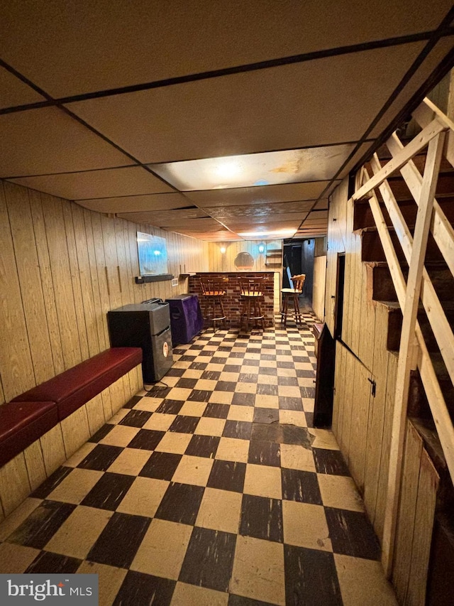 hallway with a drop ceiling and wood walls