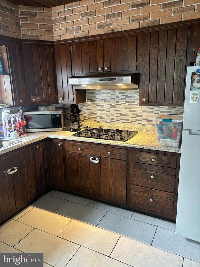 kitchen with dark brown cabinets, black gas stovetop, and white fridge