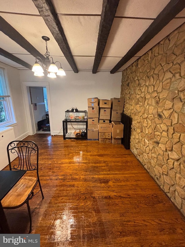 interior space featuring a notable chandelier, beam ceiling, and dark wood-type flooring