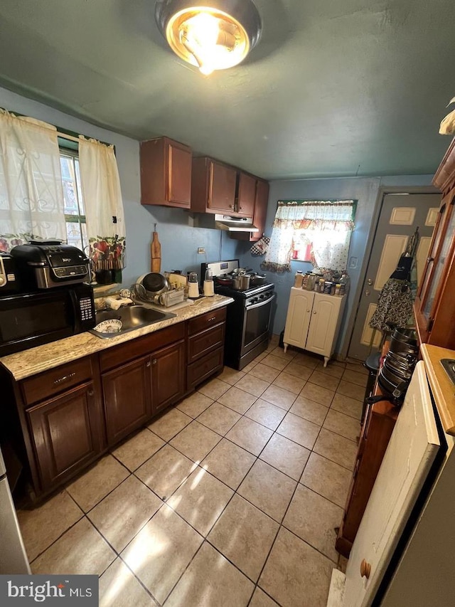 kitchen featuring light tile patterned floors, sink, and stainless steel range with electric cooktop