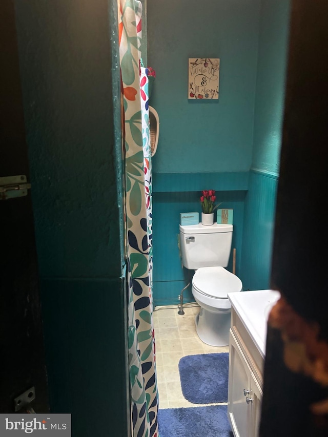 bathroom featuring a shower with curtain, vanity, tile patterned flooring, and toilet