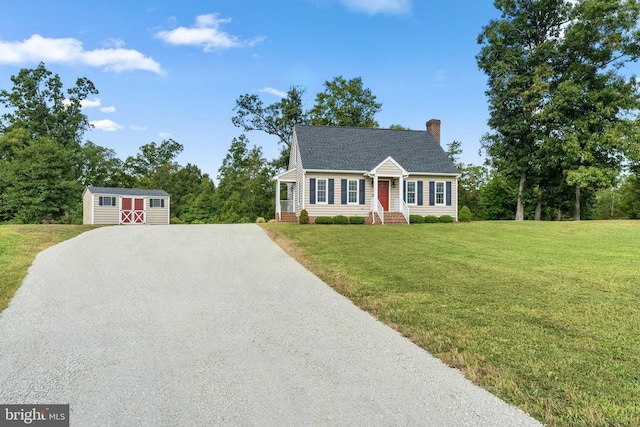 cape cod-style house featuring a front yard and a storage unit