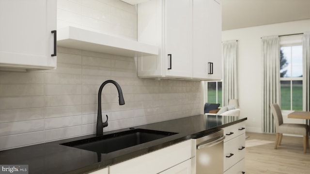 kitchen featuring light wood-type flooring, tasteful backsplash, stainless steel dishwasher, sink, and white cabinets