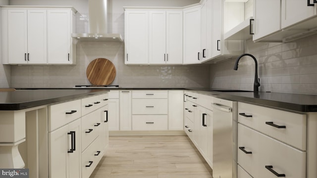 kitchen with white cabinets, light wood-type flooring, and wall chimney range hood