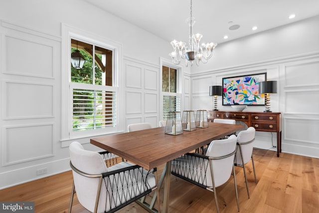 dining space with light hardwood / wood-style flooring and a notable chandelier