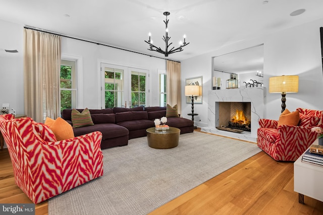 living room with wood-type flooring, a notable chandelier, and a high end fireplace