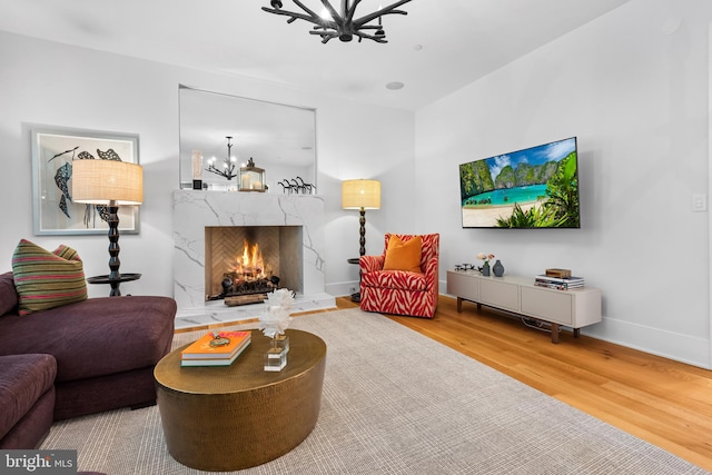 living room featuring wood-type flooring, a chandelier, and a high end fireplace