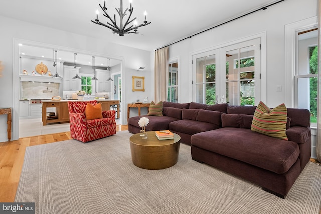 living room with light wood-type flooring, a healthy amount of sunlight, and a notable chandelier