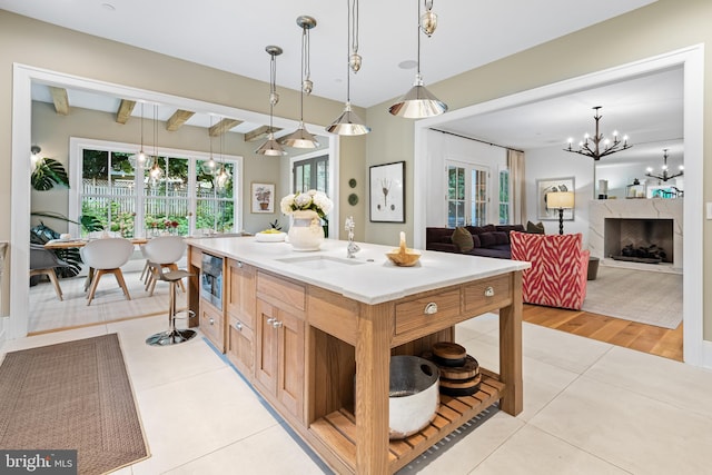 kitchen with pendant lighting, light hardwood / wood-style floors, a center island, beam ceiling, and a fireplace