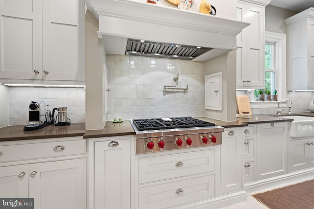 kitchen featuring white cabinetry, backsplash, stainless steel gas stovetop, premium range hood, and sink