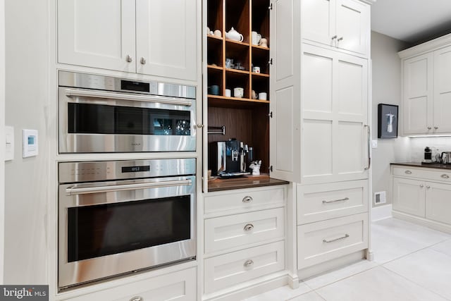 kitchen featuring white cabinetry, stainless steel double oven, and light tile patterned floors