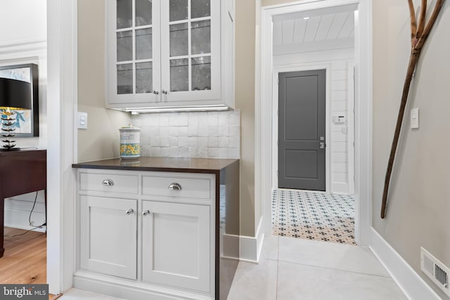 bar with white cabinets, backsplash, and light tile patterned floors