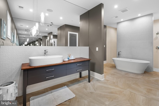 bathroom featuring a bathing tub, vanity, and tile walls