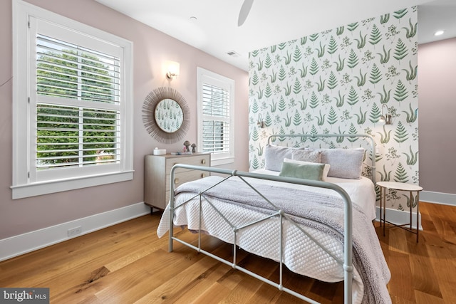 bedroom with multiple windows, wood-type flooring, and ceiling fan