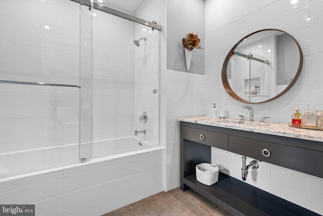 bathroom featuring tile walls, enclosed tub / shower combo, vanity, and tile patterned floors