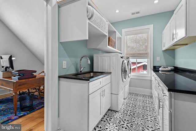 kitchen with white cabinets, light hardwood / wood-style flooring, sink, and washing machine and dryer