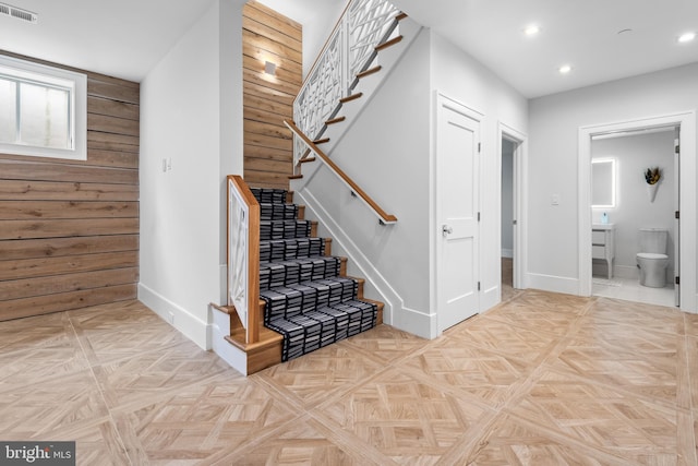 stairway with wood walls and parquet floors