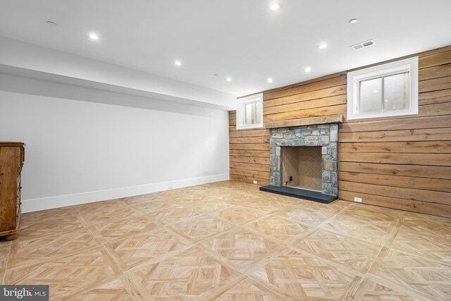 unfurnished living room with light parquet flooring, a fireplace, and wood walls