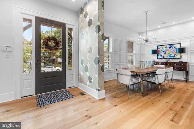 entryway with light hardwood / wood-style flooring and a notable chandelier