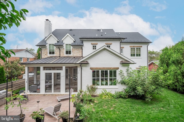 back of property featuring a yard, a sunroom, and a patio area