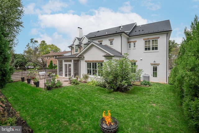 back of house with cooling unit, a yard, a patio area, and a fire pit