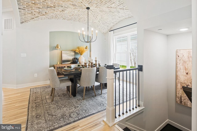 dining space featuring brick ceiling, a notable chandelier, wood finished floors, and visible vents