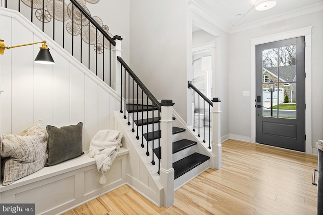 foyer with crown molding, light wood-style floors, baseboards, and stairway