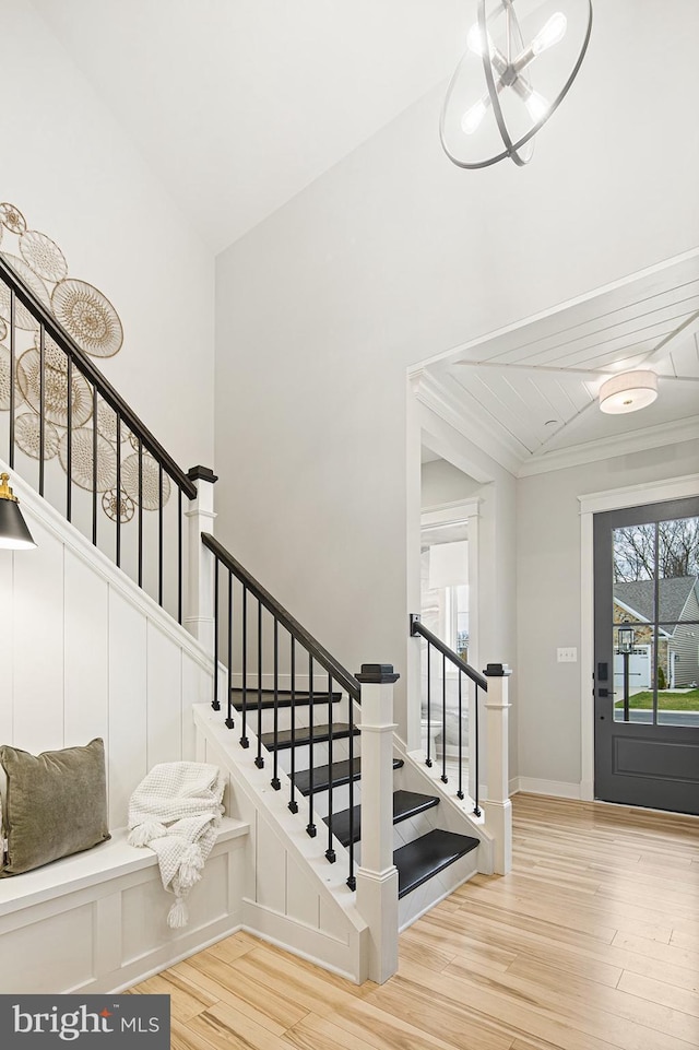 stairway with baseboards, ornamental molding, wood finished floors, and lofted ceiling