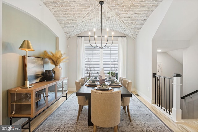 dining room with baseboards, a notable chandelier, wood finished floors, and lofted ceiling