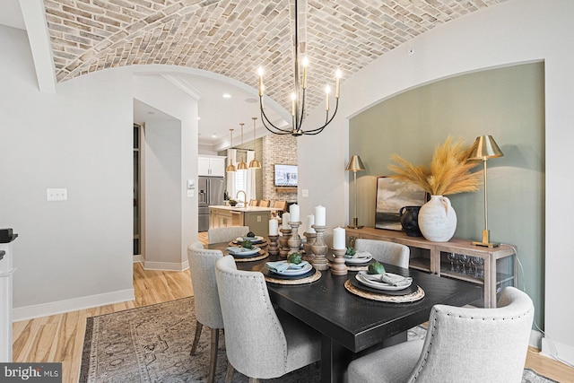 dining room featuring brick ceiling, a notable chandelier, lofted ceiling, and light wood-type flooring