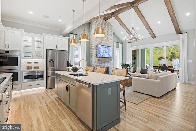kitchen with beam ceiling, a kitchen breakfast bar, white cabinetry, a sink, and appliances with stainless steel finishes