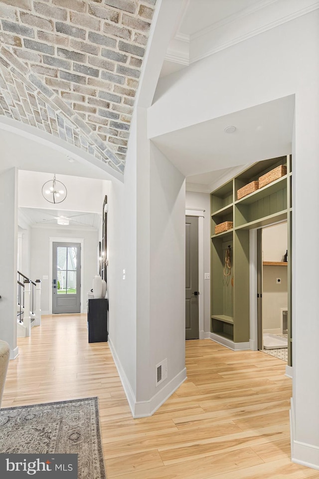 corridor with crown molding, baseboards, light wood-type flooring, brick ceiling, and visible vents