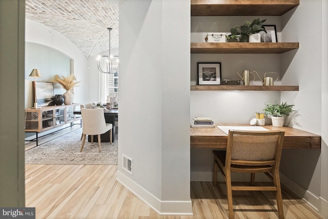 interior space with visible vents, vaulted ceiling, wood finished floors, baseboards, and an inviting chandelier
