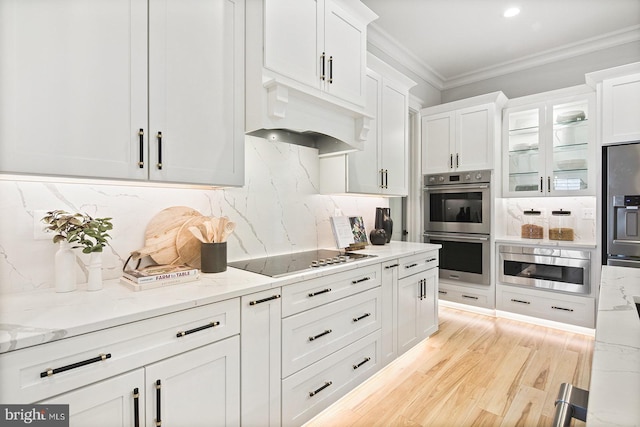 kitchen with white cabinets, crown molding, black electric stovetop, and double oven
