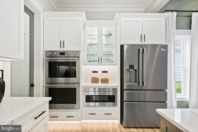 kitchen with ornamental molding, appliances with stainless steel finishes, and white cabinets
