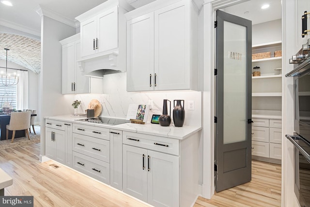 kitchen featuring light wood-type flooring, white cabinetry, stainless steel oven, and under cabinet range hood