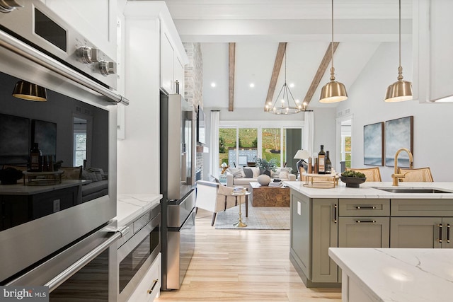kitchen featuring beamed ceiling, open floor plan, a sink, gray cabinetry, and stainless steel appliances