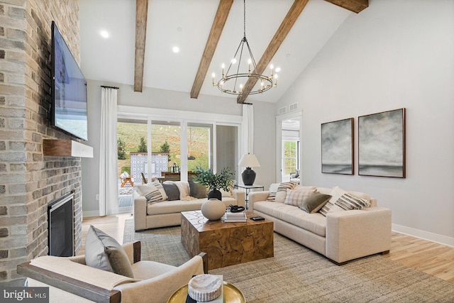 living area featuring a brick fireplace, beam ceiling, high vaulted ceiling, a chandelier, and light wood-style floors