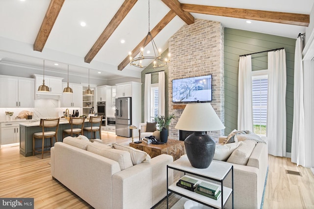 living room with visible vents, light wood finished floors, a notable chandelier, and vaulted ceiling with beams