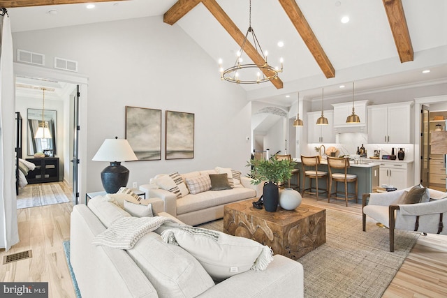 living area featuring visible vents, a notable chandelier, and high vaulted ceiling