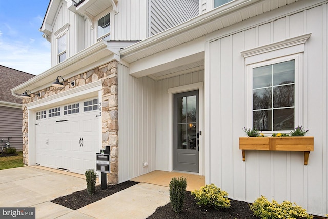view of exterior entry featuring an attached garage, driveway, and stone siding