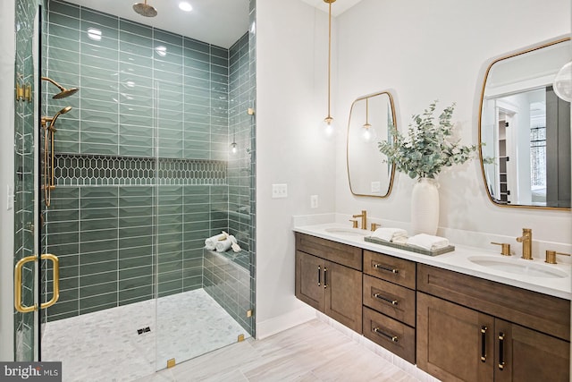 full bath featuring double vanity, a sink, baseboards, and a shower stall