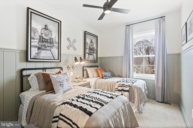 bedroom with carpet flooring, a ceiling fan, and wainscoting