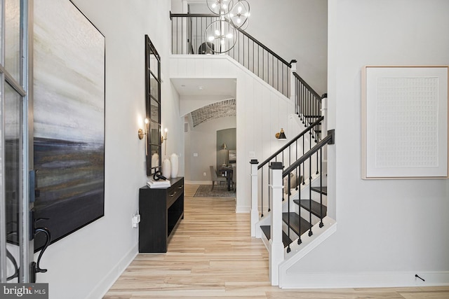 entryway with a towering ceiling, wood finished floors, baseboards, stairway, and arched walkways