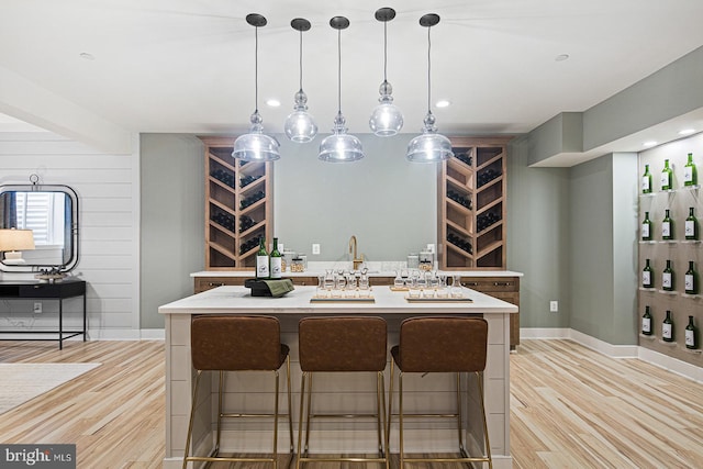 kitchen featuring a kitchen bar, pendant lighting, a center island, light countertops, and light wood-style flooring