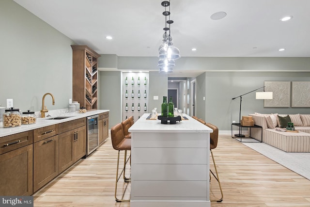 kitchen with open floor plan, a kitchen breakfast bar, light wood-type flooring, a center island, and a sink