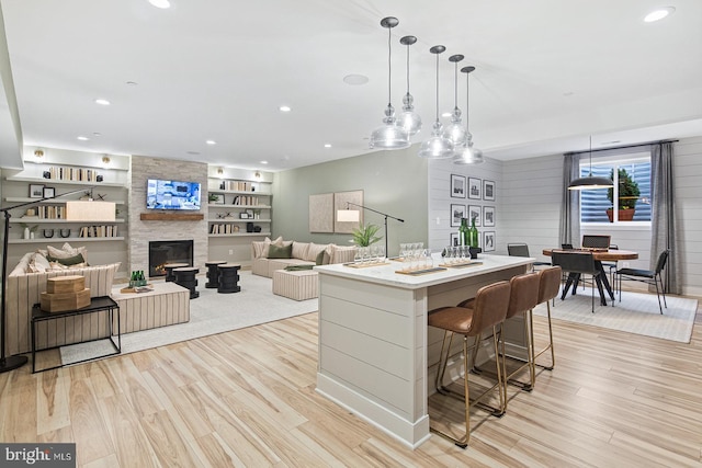 kitchen featuring a center island, recessed lighting, a large fireplace, light wood-style flooring, and hanging light fixtures