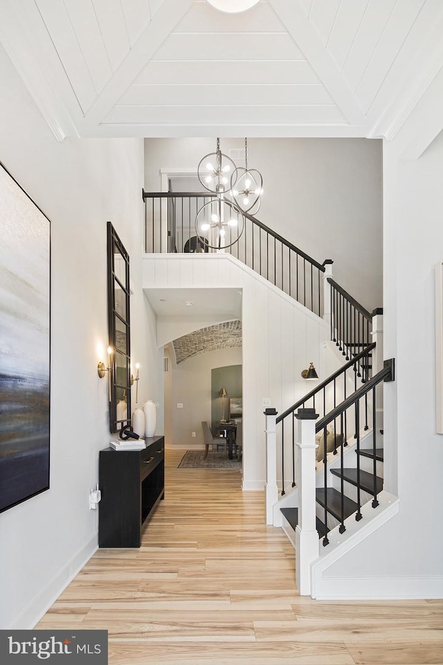 interior space with beam ceiling, wood finished floors, stairway, baseboards, and a chandelier