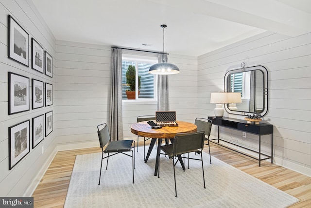dining space featuring wood finished floors and wooden walls